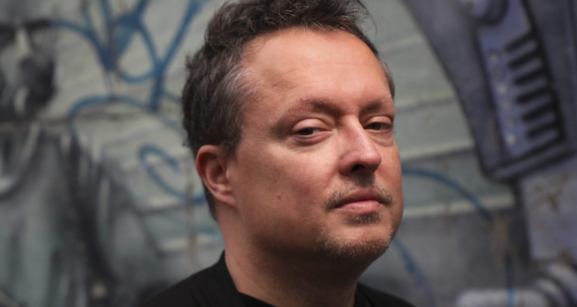 Mike Ward poses for a photo in front of some graffiti.