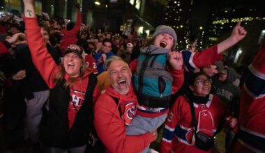 A woman, man and child cheer at the front of a large outdoor crowd of Canadiens fans.