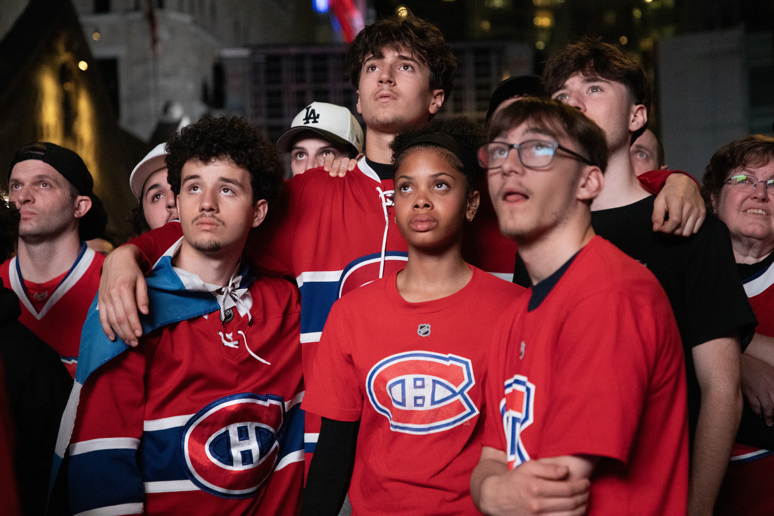 Unhappy Montreal Canadiens fans watch an unseen screen at an outdoor watch party.