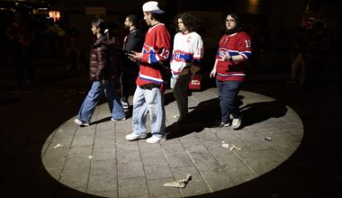 Five Canadiens fans walk through an illuminated circle of pavement at night.