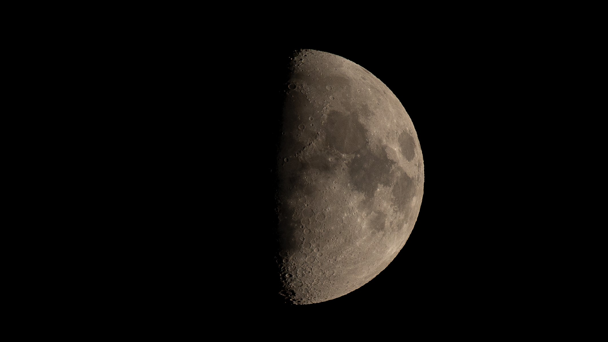 half illuminated moon, the left is bathed in shadow while the right is lit up and covered in craters.