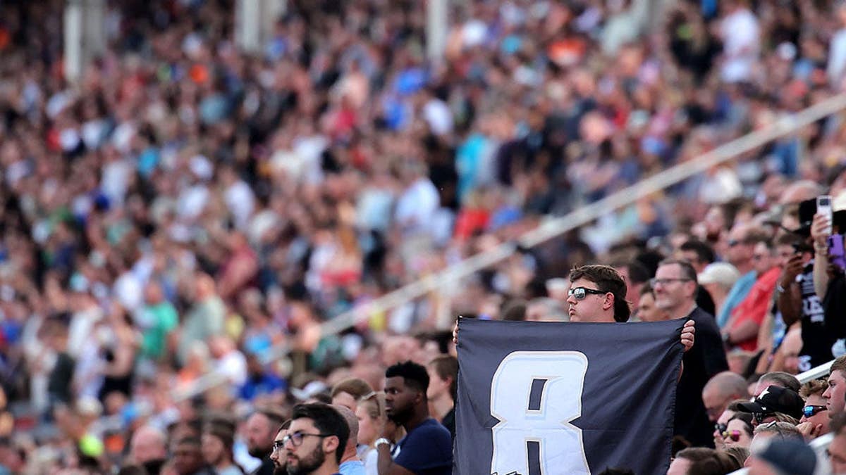 NASCAR fan holding a #8 flag in grandstands at Charlotte Motor Speedway