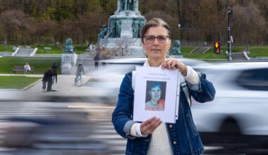 Julie Labelle-Patenaude holds up a picture of Concepción Cortacans against backdrop of monument on Parc Ave. with cars driving by.