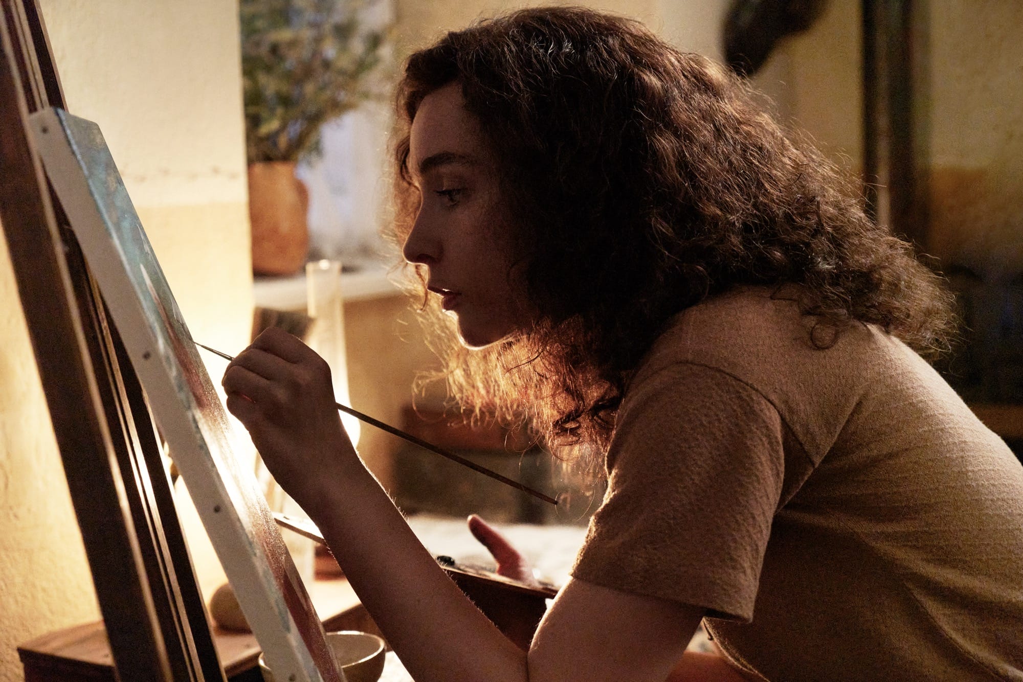 a white woman with dark curly hair painting