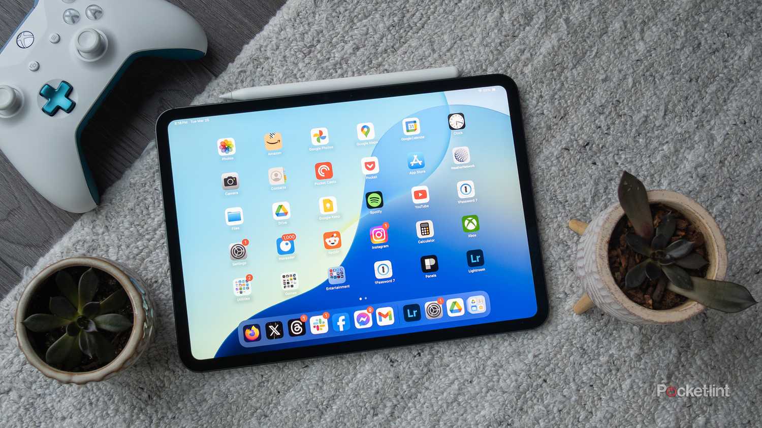 An M4 iPad Pro on a rug next to an Xbox controller.