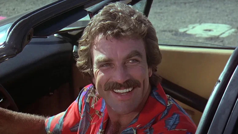 Tom Selleck smiling in car as Thomas Magnum in Magnum P.I.