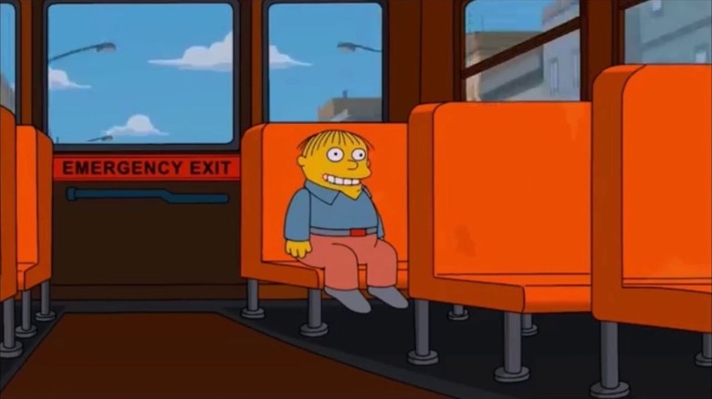 Ralph Wiggum sits at the back of the school bus with a smile on his face in a scene from the Family Guy/Simpsons crossover.