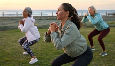 Women doing squats as part of yoga as strength training together outdoors in the summer by the sea