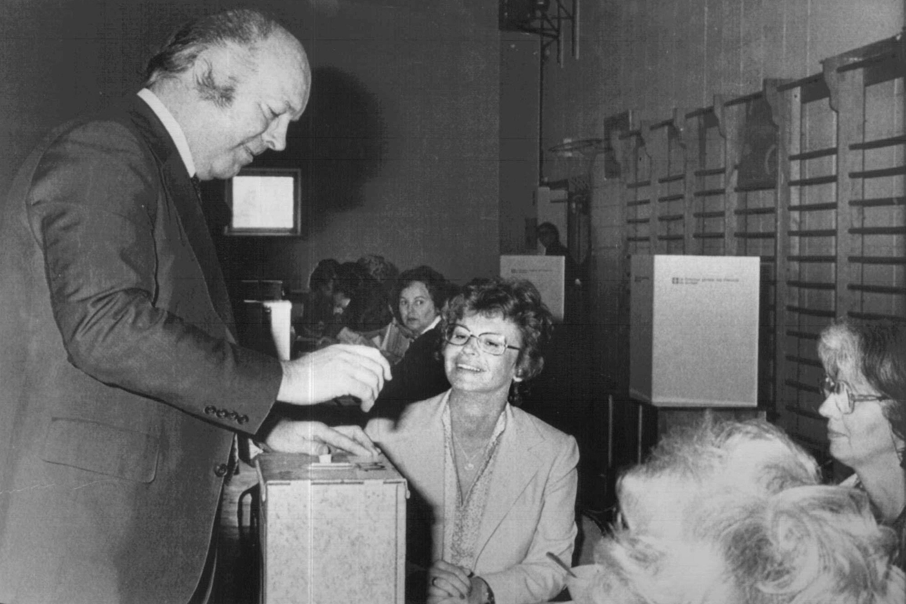 Claude Morin places a ballot in a ballot box in a black and white photo