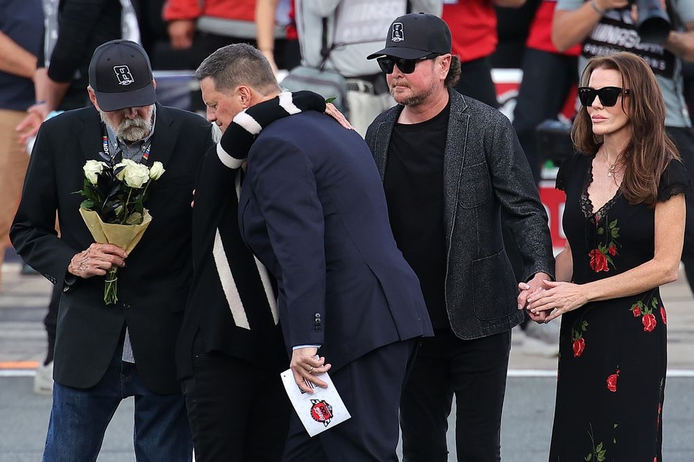 NASCAR Chief Executive Officer Steve O’Donnell embraces Gaye Busch during the remembrance ceremony for Kyle Busch, who passed away suddenly at the age of 41, his father, Tom Busch (L) brother, NASCAR Hall of Famer Kurt Busch and Lyda Moore on the grid prior to the NASCAR Cup Series Coca-Cola 600