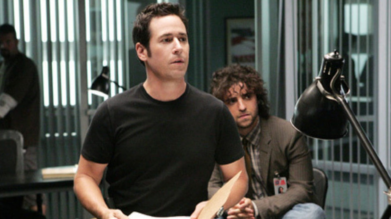 Don Eppes standing in front of Charlie Eppes in an office