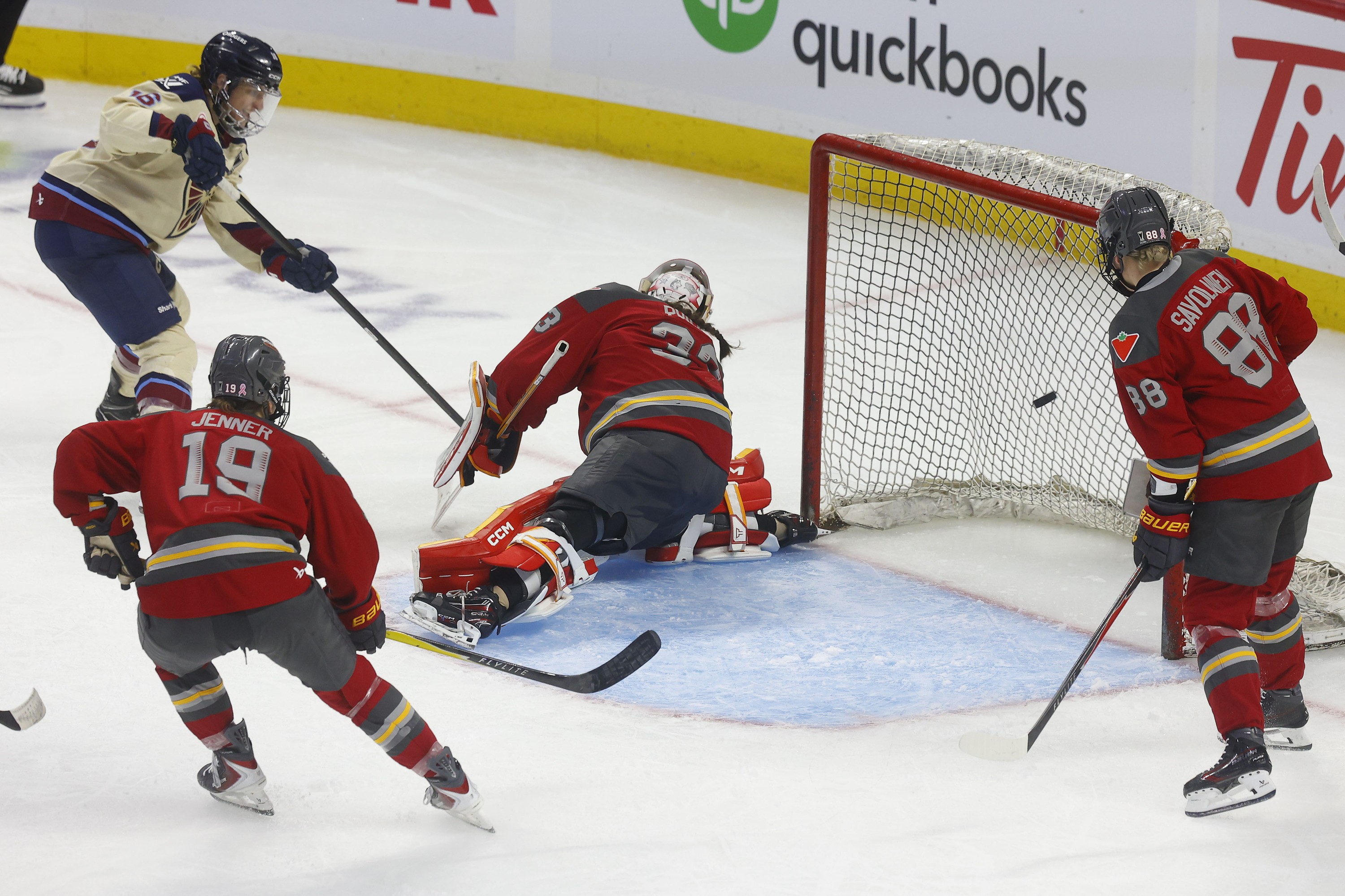The puck flies into the net behind the Ottawa charge goaltender as Hayley Scamurra of the Victoire follows through on the shot.