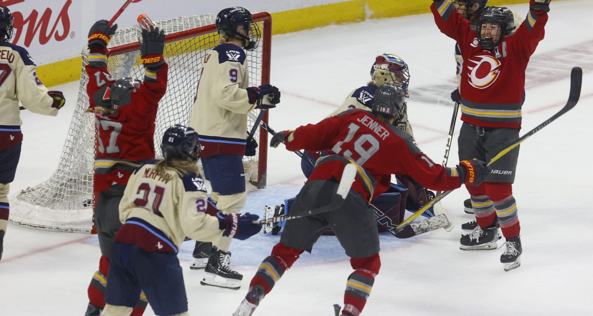 Ottawa Charge's Rebecca Leslie throws her hands up in the air as teammates also celebrate outside the Montreal net