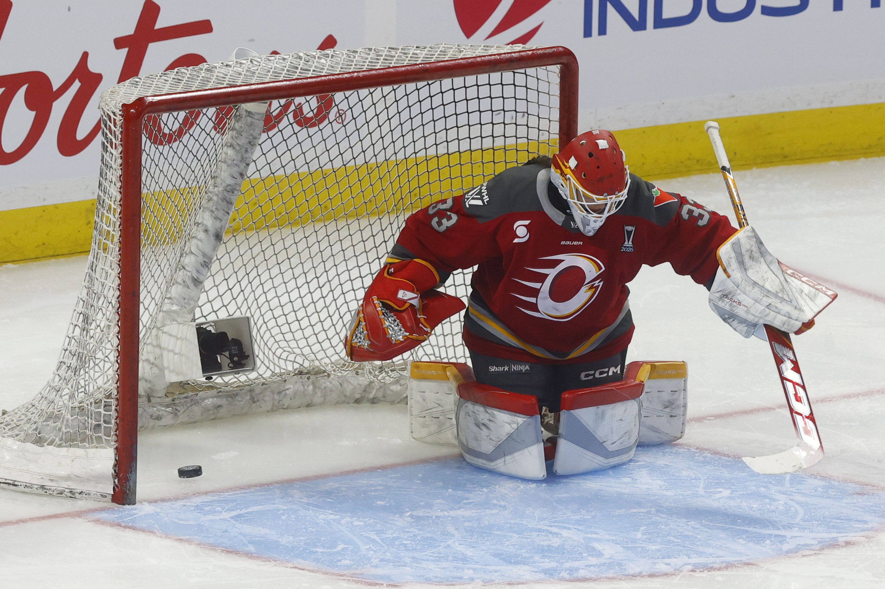 The puck is behind an Ottawa Charge goaltender on her knees in the crease.