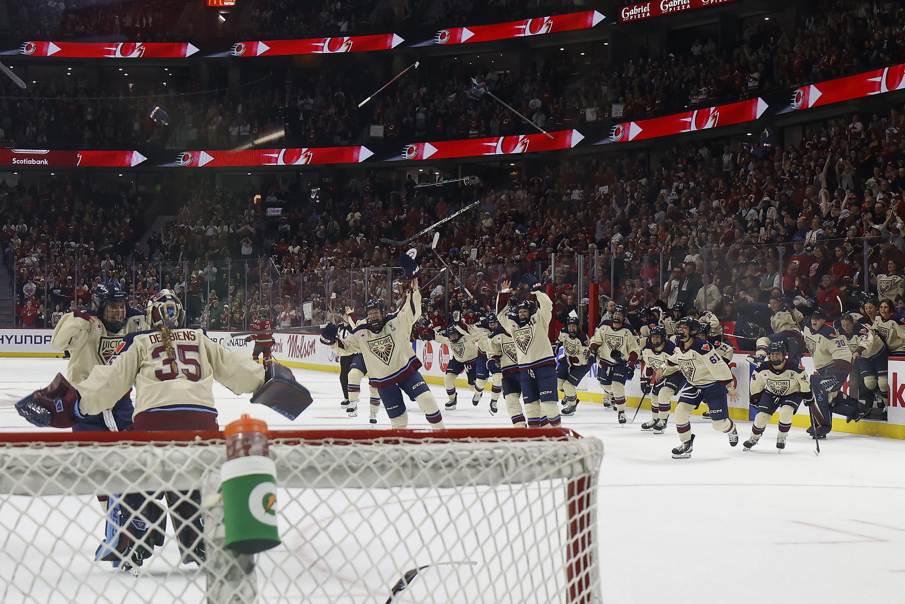 Victoire players rush on the ice in celebration.
