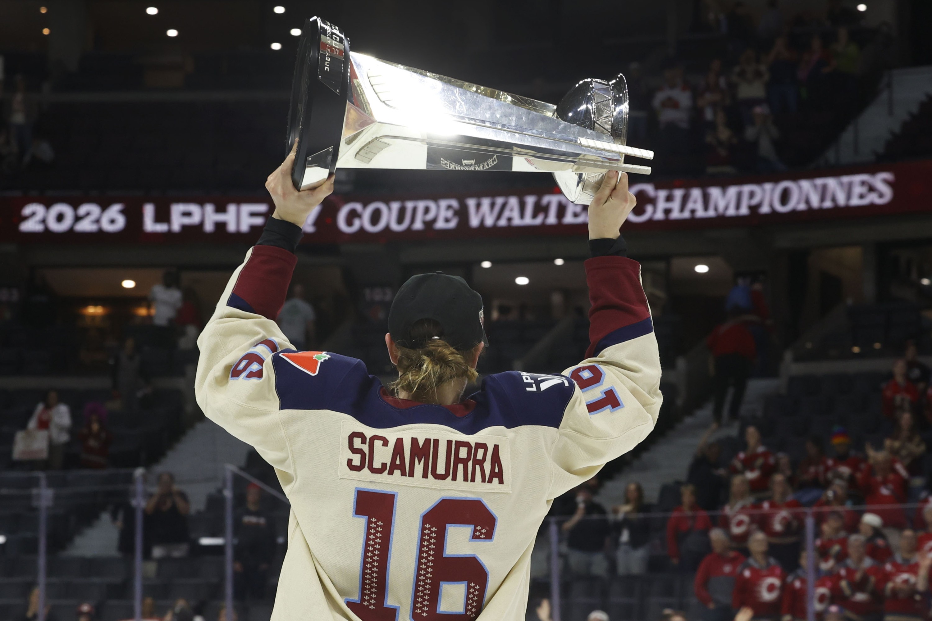 Hayley Scamurra, seen from behind, hoists the Walter Cup.