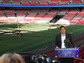 Premier David Eby speaks at B.C. Place, in front of the freshly-installed natural grass playing surface, during a press conference on Tuesday.