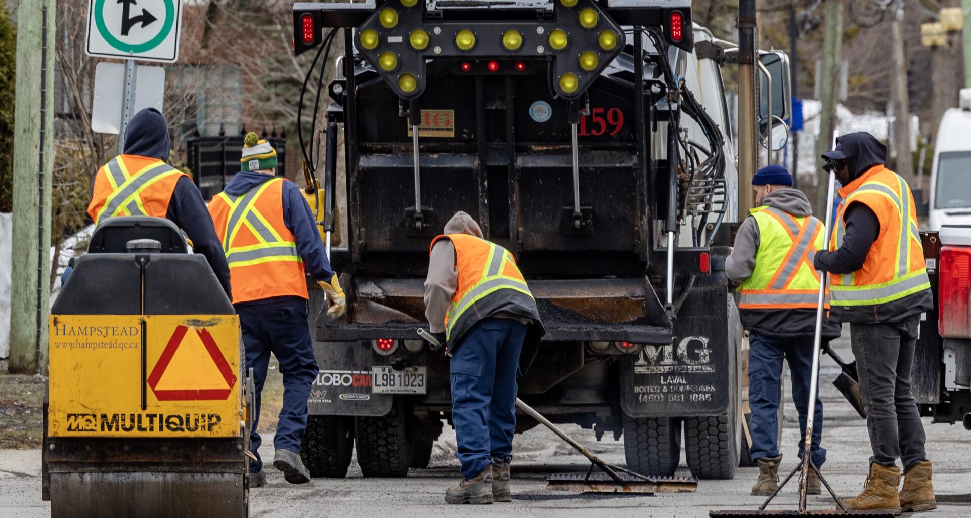 Work crew patches potholes behind a big truck