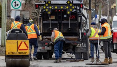 Work crew patches potholes behind a big truck