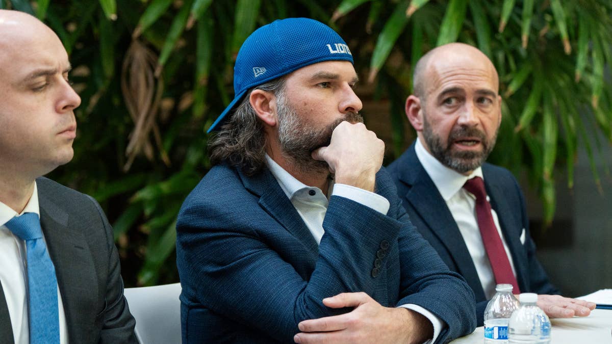 Detroit Lions fan Ryan Kennedy seated with attorneys Sean Murphy and Shawn Head in an office.