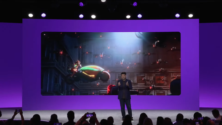 A man on stage in front of a screen showing a 3D animation
