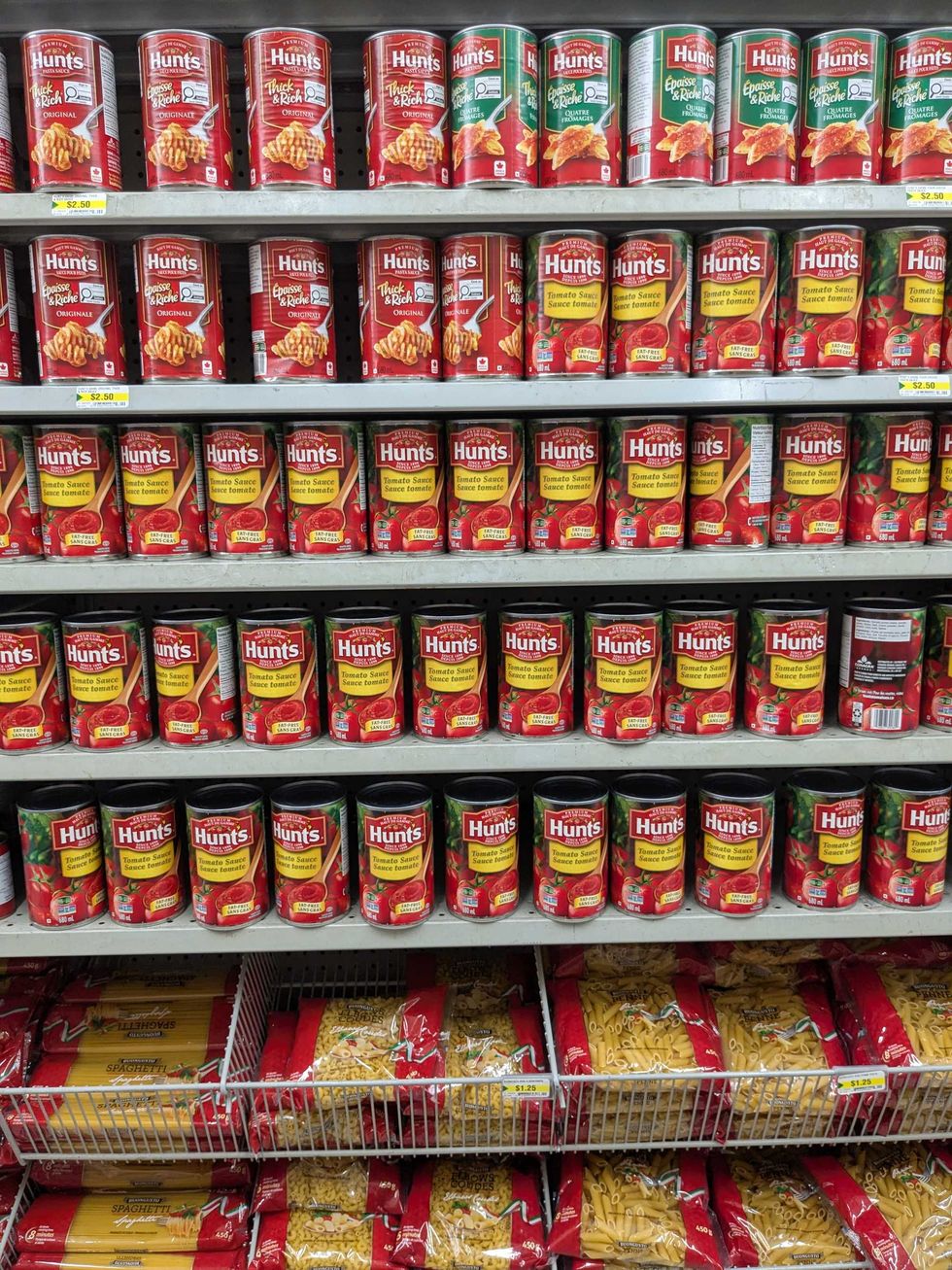 Shelves of tomato sauce in cans and pasta