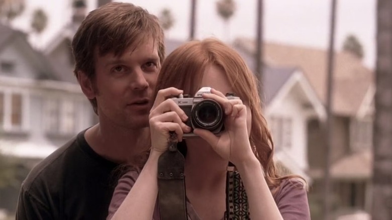 Nate Fisher whispers in the ear of Claire Fisher as she takes a photograph