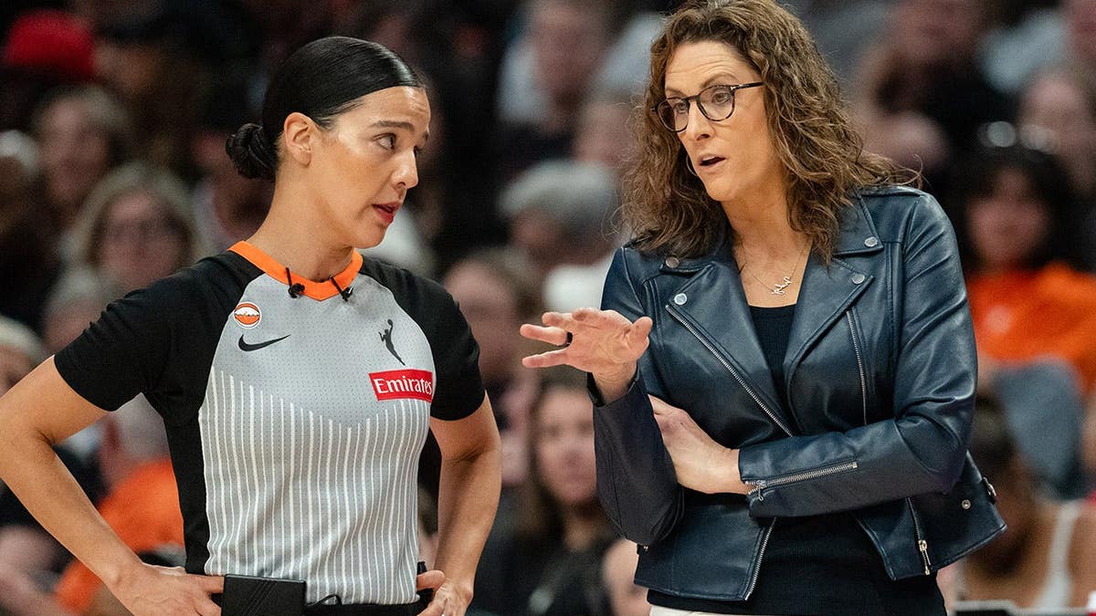 Head Coach Stephanie White talking to a referee on the sideline during a basketball game.