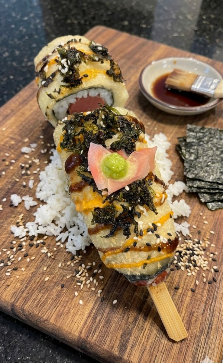An Asian-fusion corn dog wrapping sushi elements in a crispy, golden cornmeal batter coating.