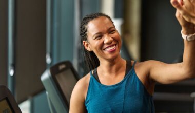 Woman high fiving after doing treadmill workout, smiling and wearing workout clothes