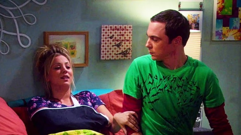 Penny and Sheldon sitting on a bed and talking