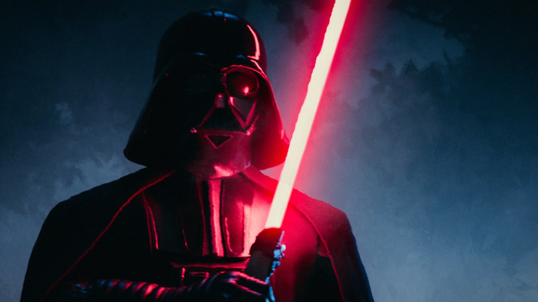 Darth Vader raises his red lightsaber in a shadowy forest