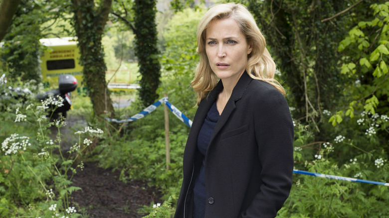Stella Gibson surrounded by greenery at crime scene