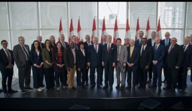 Government, business and post-secondary leaders gathered together on stage, smiling.