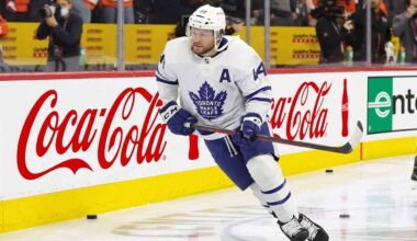 Toronto Maple Leafs defenseman Morgan Rielly (#44) skating with the puck during an NHL game, featuring Coca-Cola and Enterprise advertising on the arena boards.