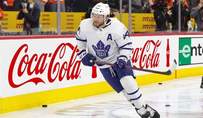 Toronto Maple Leafs defenseman Morgan Rielly (#44) skating with the puck during an NHL game, featuring Coca-Cola and Enterprise advertising on the arena boards.
