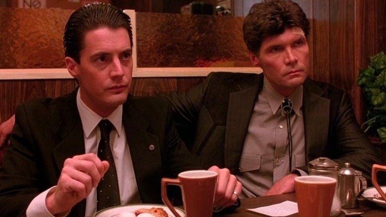 Dale Cooper sits in a diner booth next to Ed Hurley