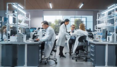 Several researchers are working alone or engaging in discussion in a pharmaceutical lab.