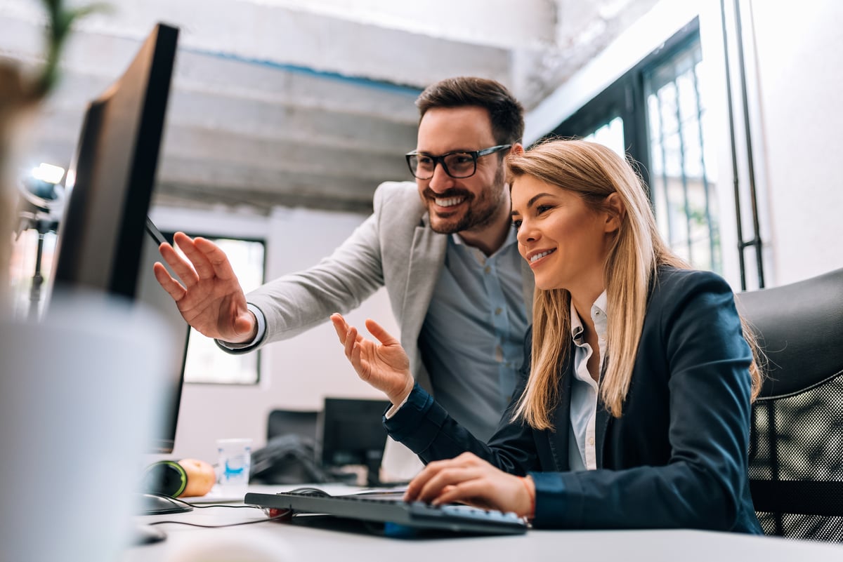 Two investors look at something on a computer.
