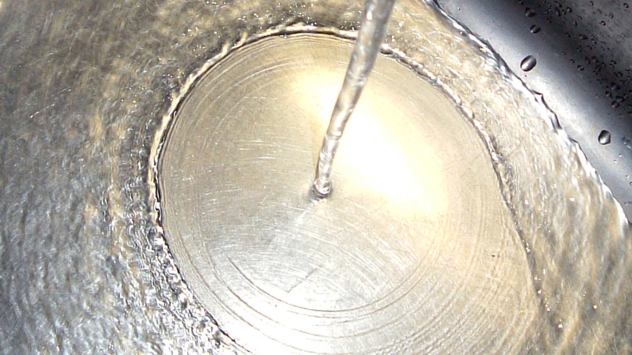 water pours into a metal basin, creating a shallow ring in a deep pool