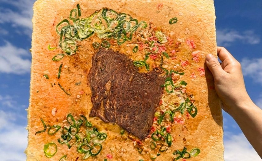A massive, thin Japanese rice cracker topped with premium wagyu beef, savory okonomiyaki sauce, mayo, and green onions.