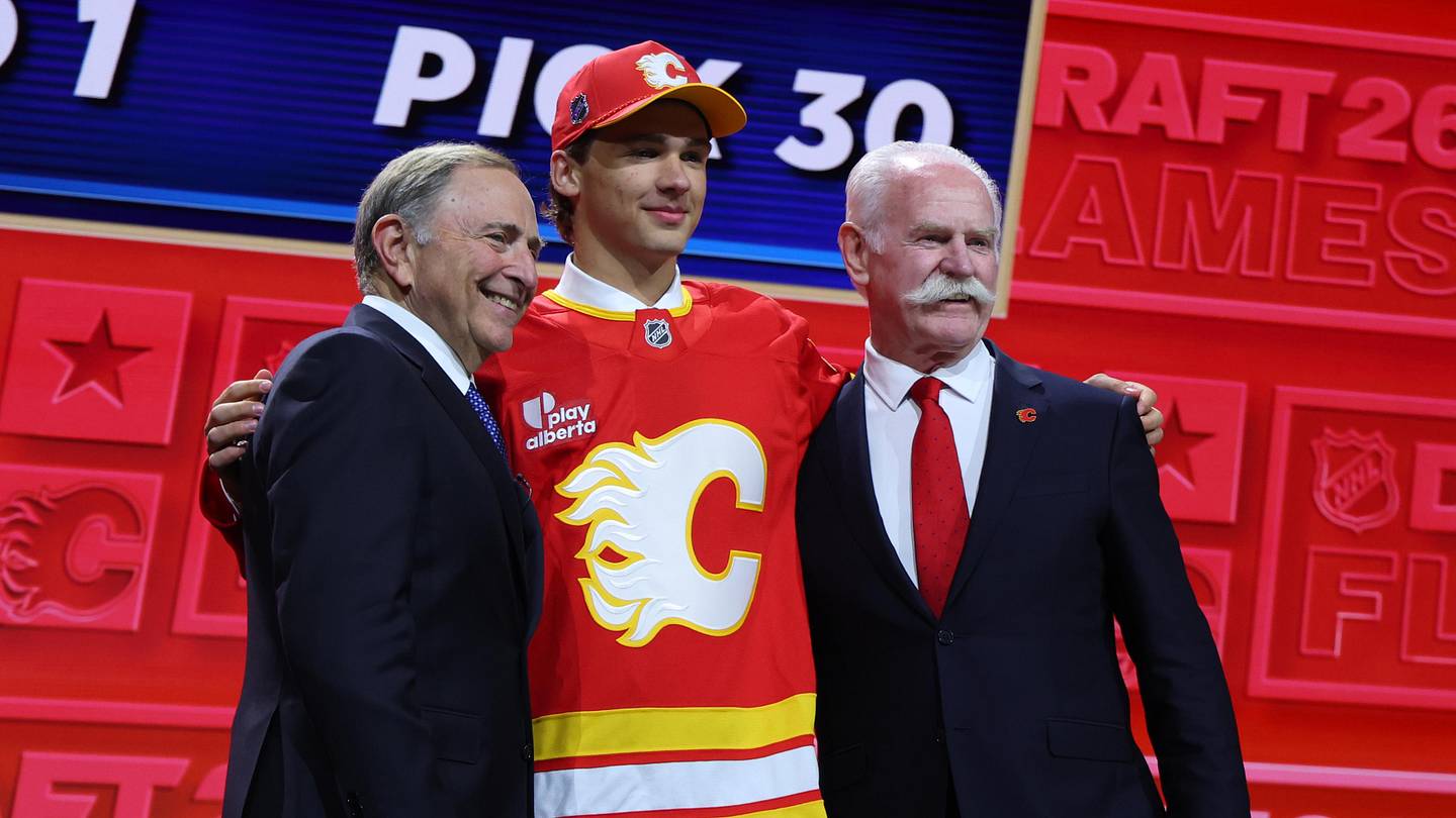 Jun 26, 2026; Buffalo, New York, USA; Jack Hextall reacts beside NHL commissioner Gary Bettman and former NHL player Lanny McDonald after being selected with the thirtieth pick in the first round of the 2026 NHL Draft by the Calgary Flames at KeyBank Center. Mandatory Credit: Timothy T. Ludwig-Imagn Images