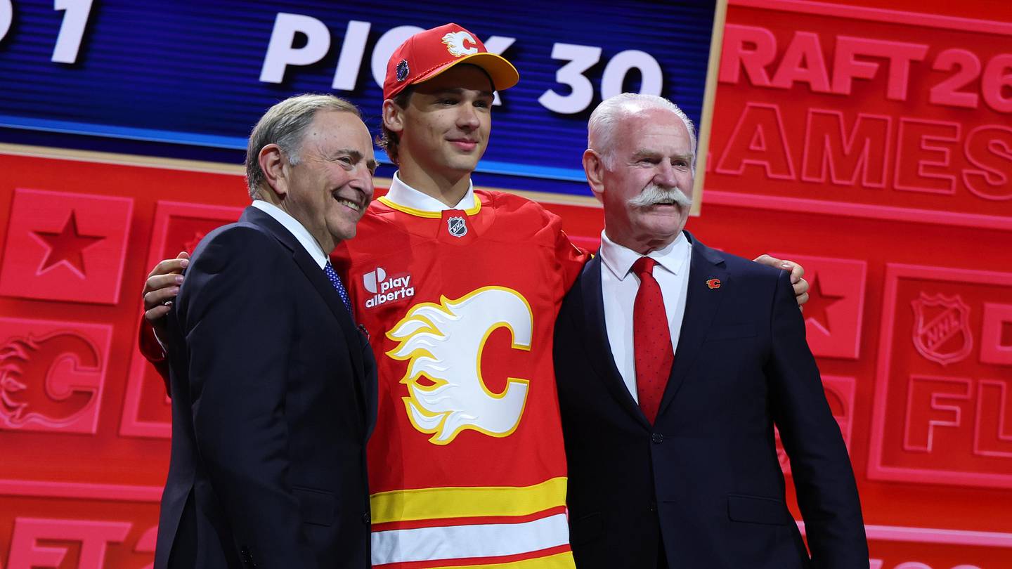 Jun 26, 2026; Buffalo, New York, USA; Jack Hextall reacts beside NHL commissioner Gary Bettman and former NHL player Lanny McDonald after being selected with the thirtieth pick in the first round of the 2026 NHL Draft by the Calgary Flames at KeyBank Center. Mandatory Credit: Timothy T. Ludwig-Imagn Images