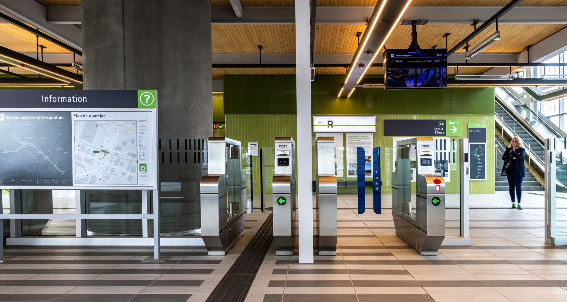 Turnstiles, escalators and information boards leading to a REM station.