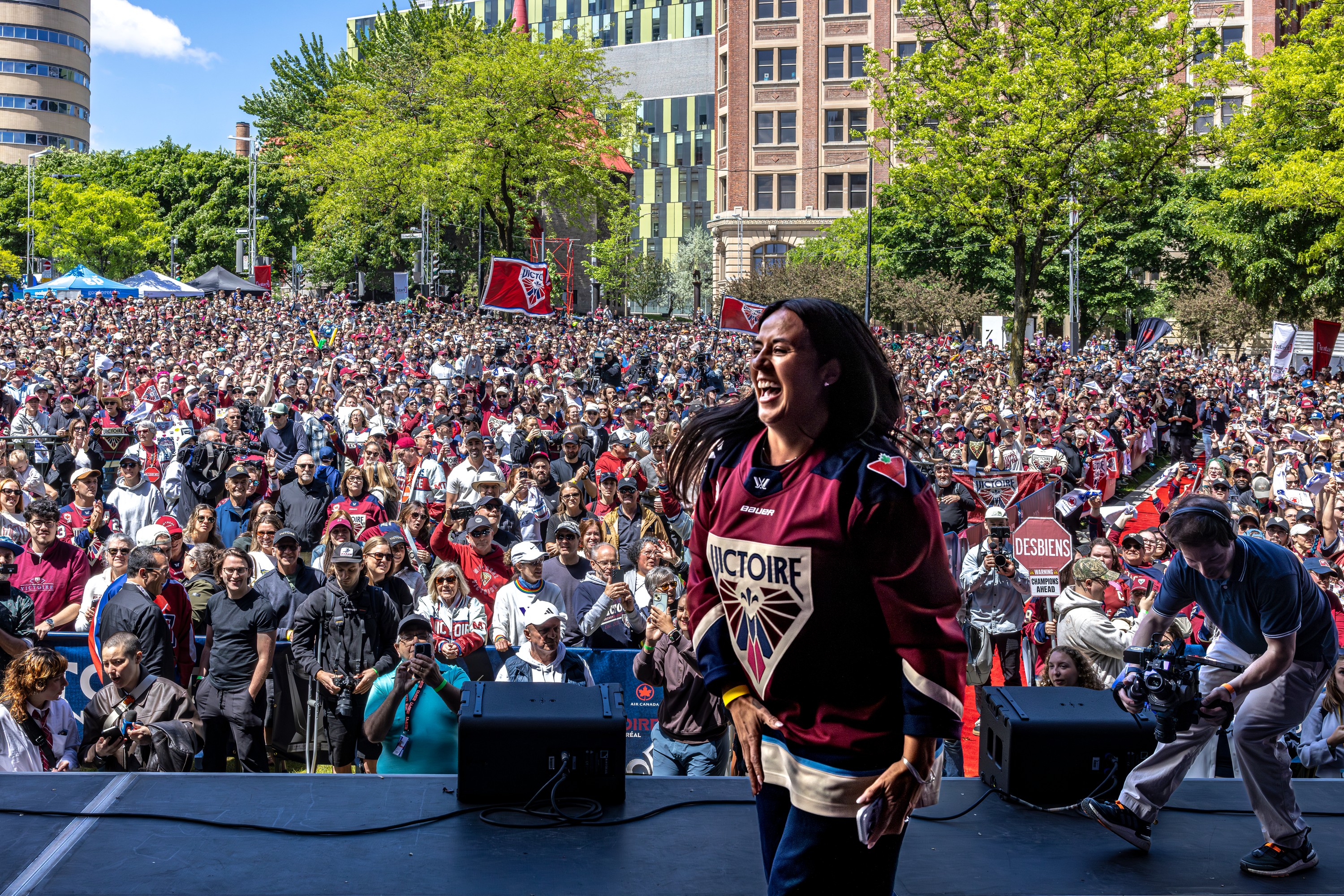 Montreal Mayor Soraya Martinez Ferrada wears a Montreal Victoire jersey on stage in front of a large crowd.