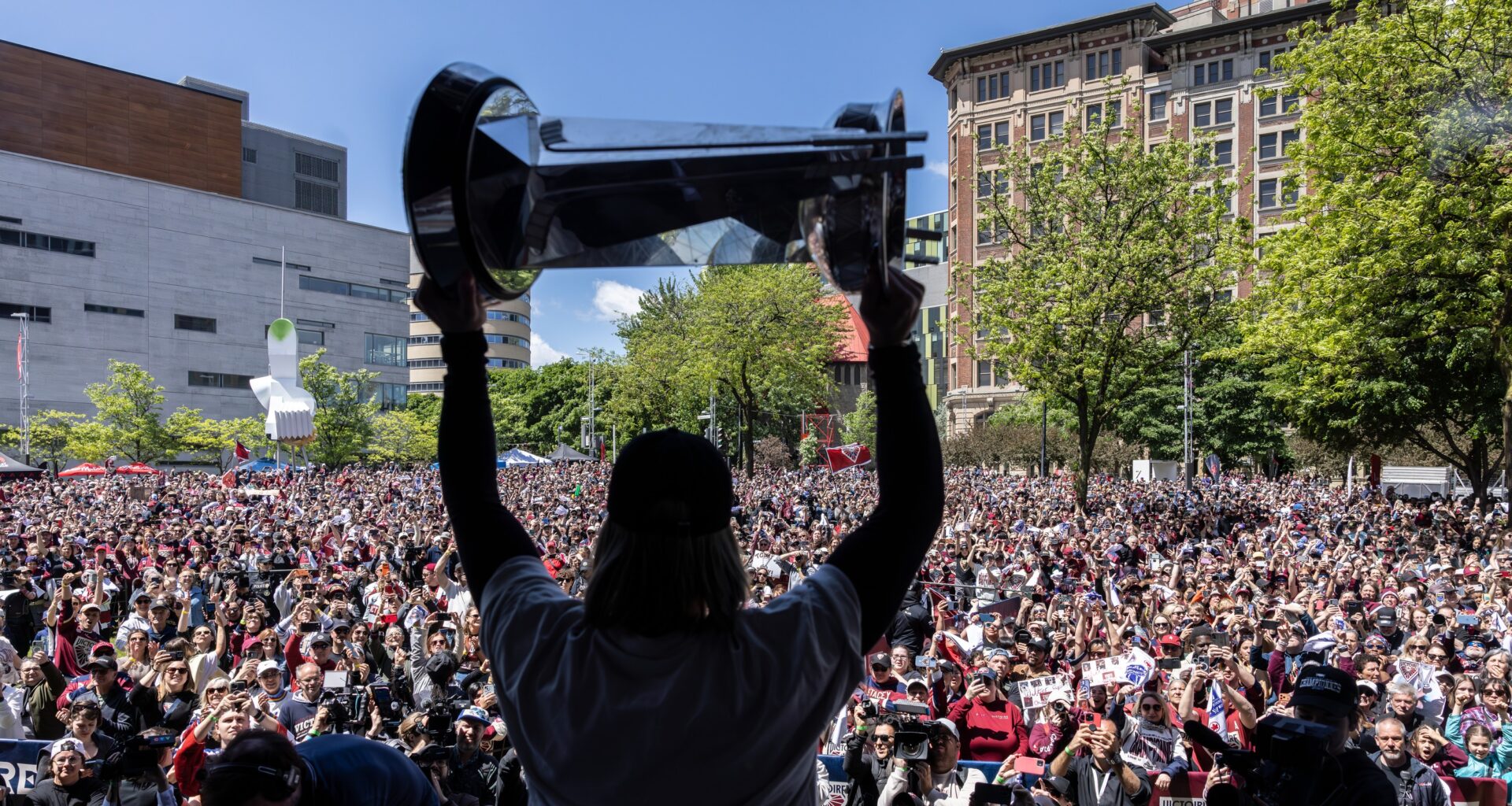 Women's hockey player hoists the championship cup in front of thousands of fans.
