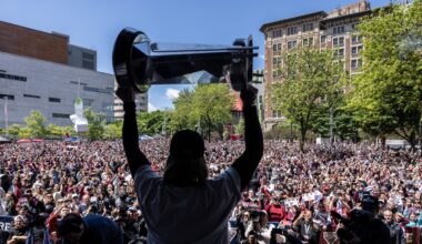 Women's hockey player hoists the championship cup in front of thousands of fans.