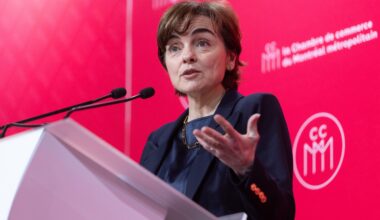Quebec Premier Christine Fréchette speaks at a podium in front of a red backdrop displaying the logo of the Chamber of Commerce of Metropolitan Montreal.