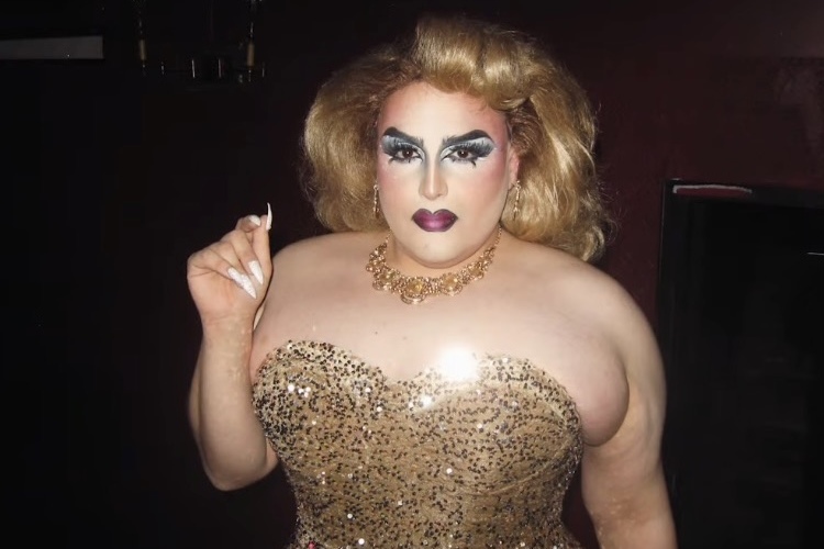 A drag artist in a glittery dress and blond hair.
