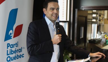 Quebec Liberal Party Leader stands at a podium with a mic in his hand.